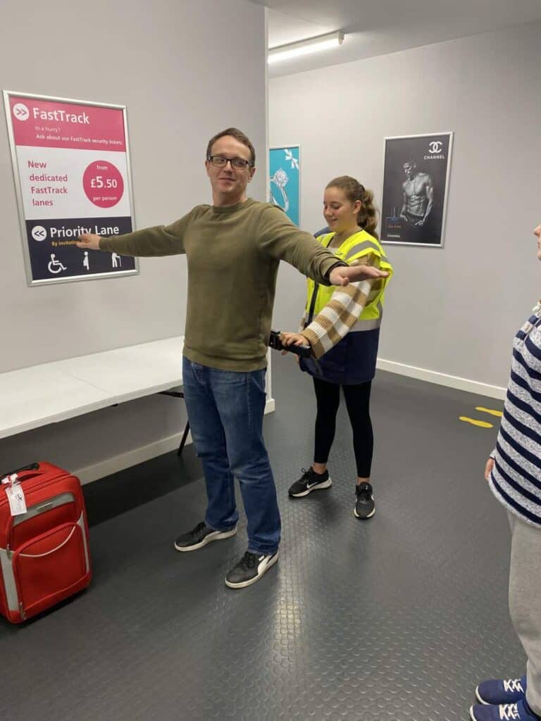 Aggie is scanning Dom through security to check for metal items 