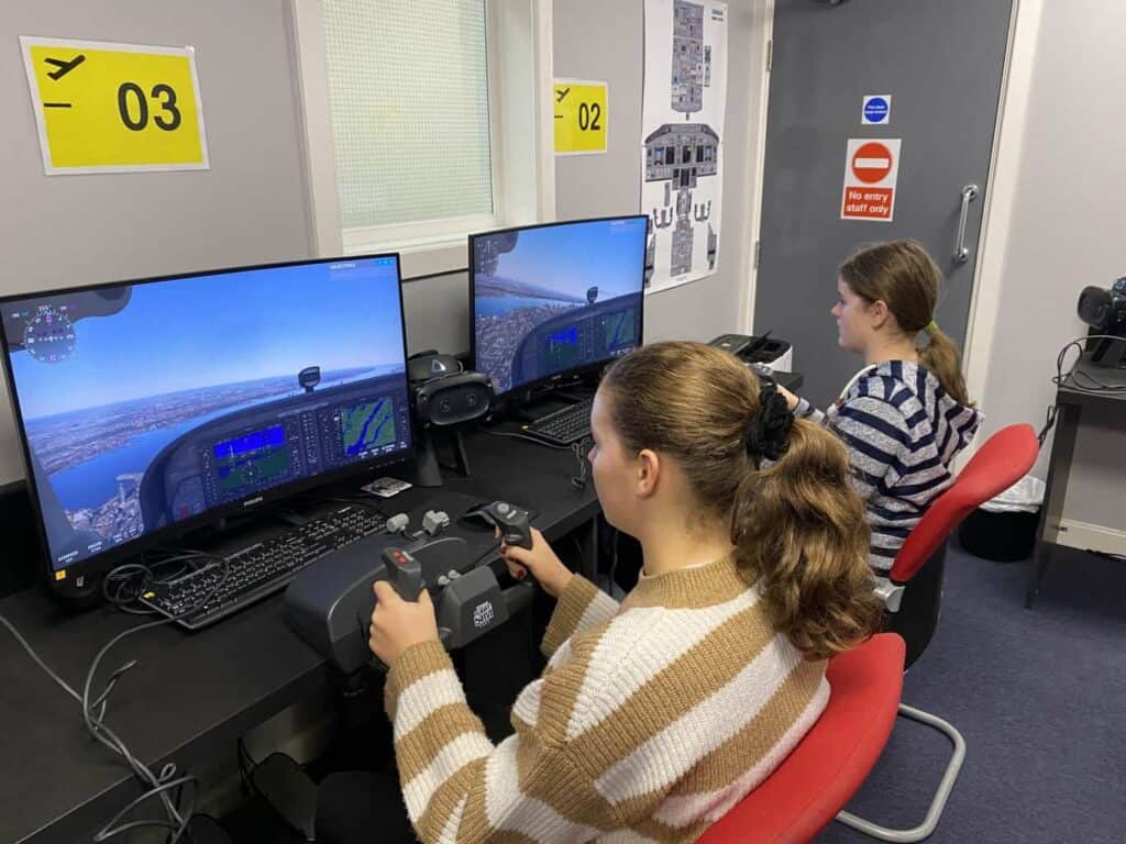 Aggie is flying a plane using a flight simulator as part of the aviation career day