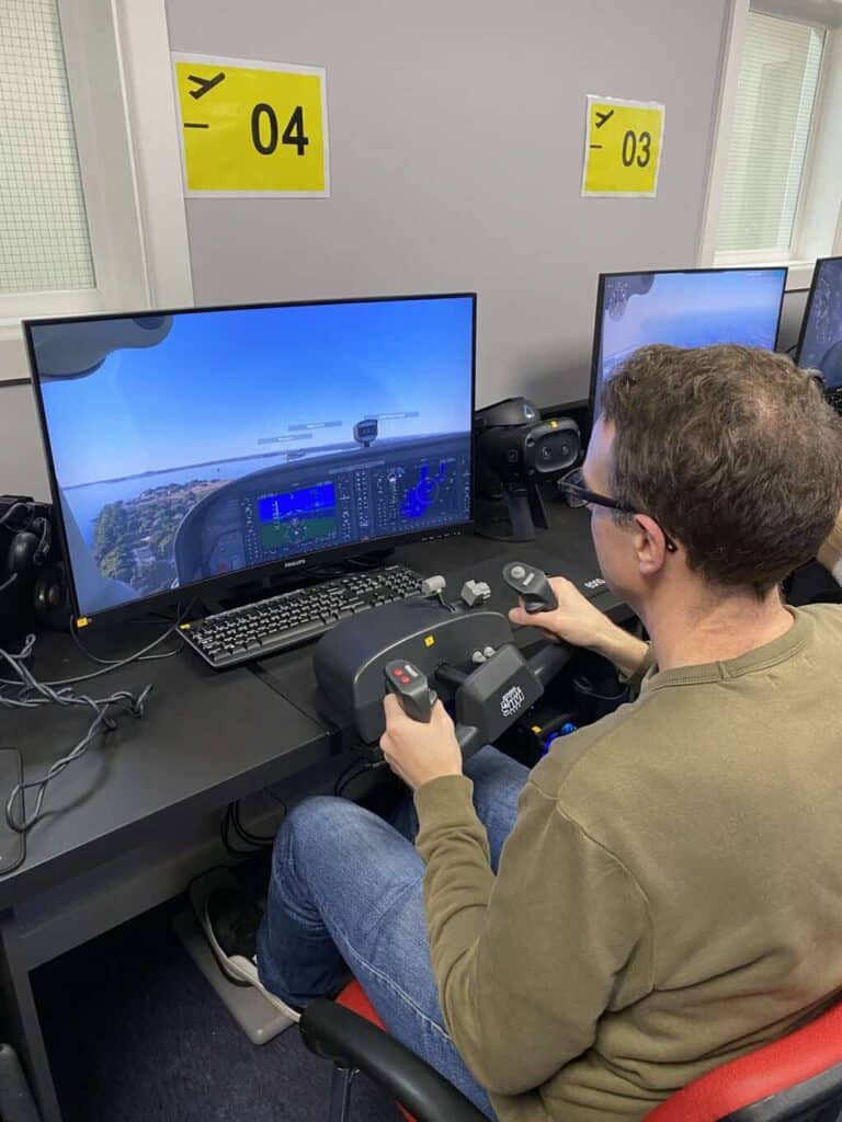 Dom is flying a plane using a flight simulator as part of the aviation career day