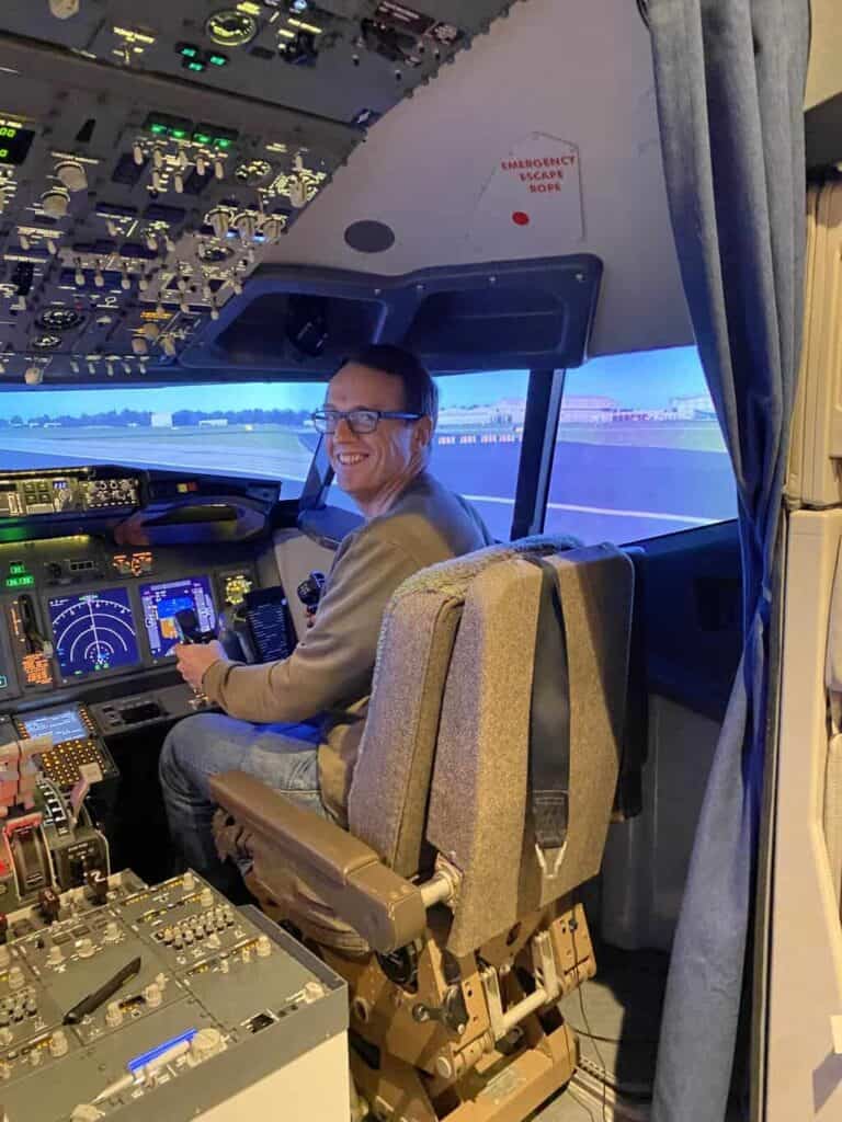 Dom is sat in the pilot chair of a flight simulator ready to the land the plane as part of the aviation career day 